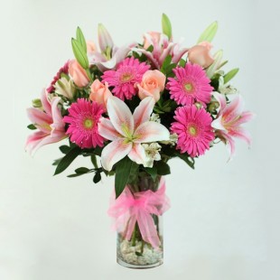 Florero de vidrio con gerberas, rosas y liliums rosados