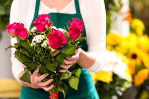 Florist hands showing red roses bouquet flowers