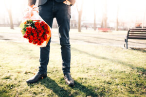 Hombre esperando con ramo de rosas en la mano.