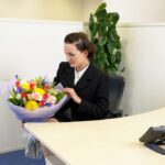 Secretaria recibiendo flores por su día.