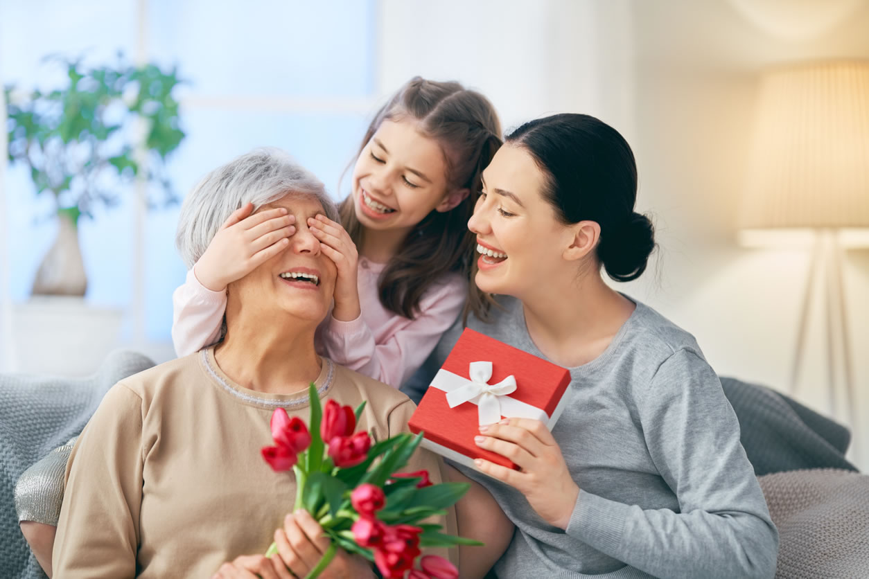 Abuela, madre e hija con flores y regalos en el día de la madre.